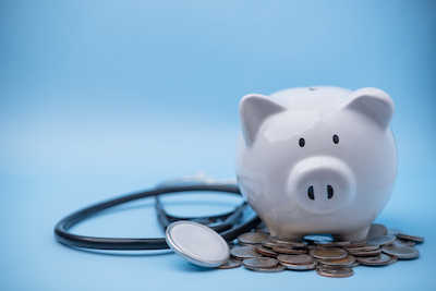 piggybank with coins beside a stethoscope